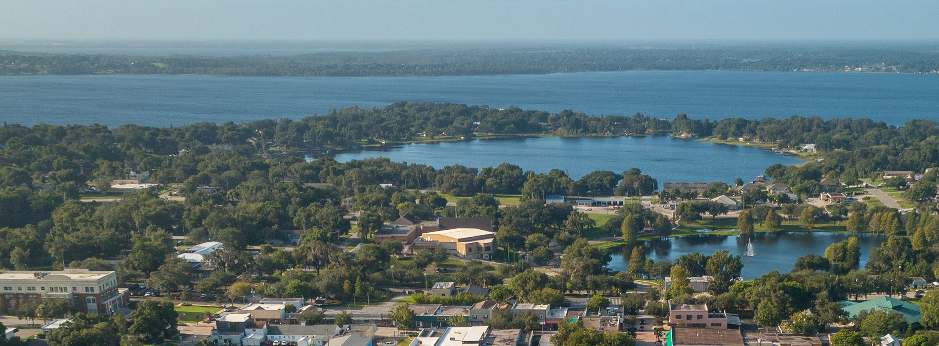 Aerial view of a cityscape with a large body of water, surrounded by suburban neighborhoods.