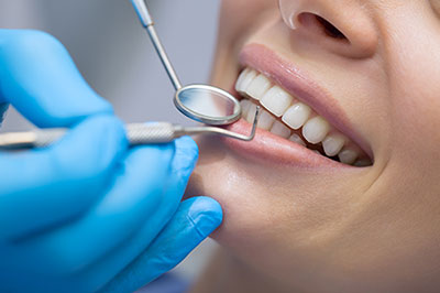 A dental professional performing a teeth cleaning procedure on a patient, with the focus on the dental tools and equipment.