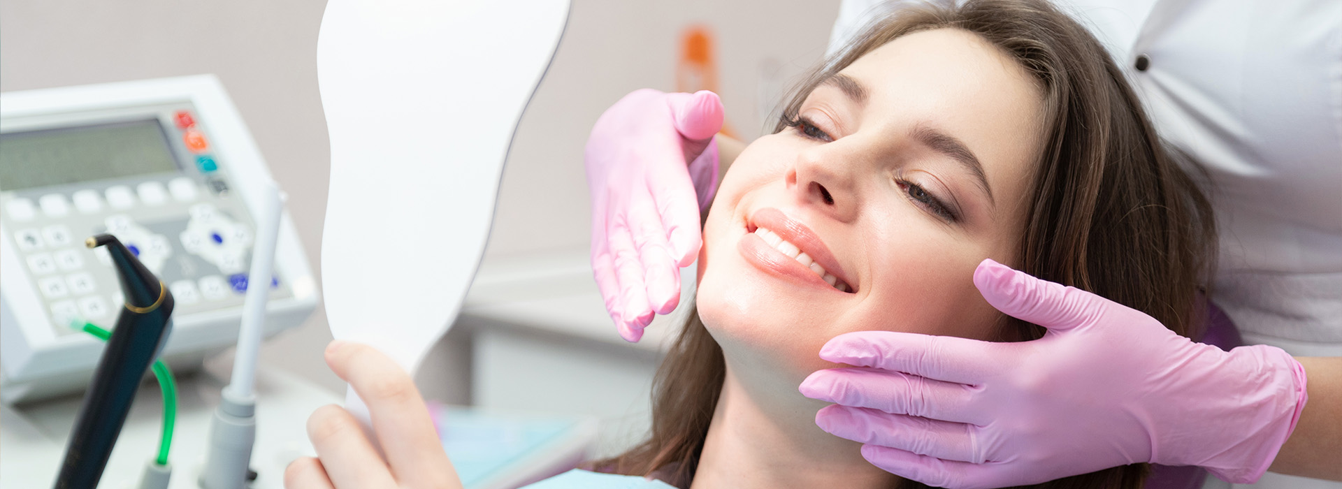 A woman receiving dental treatment, with a dentist performing the procedure and assisted by a nurse.