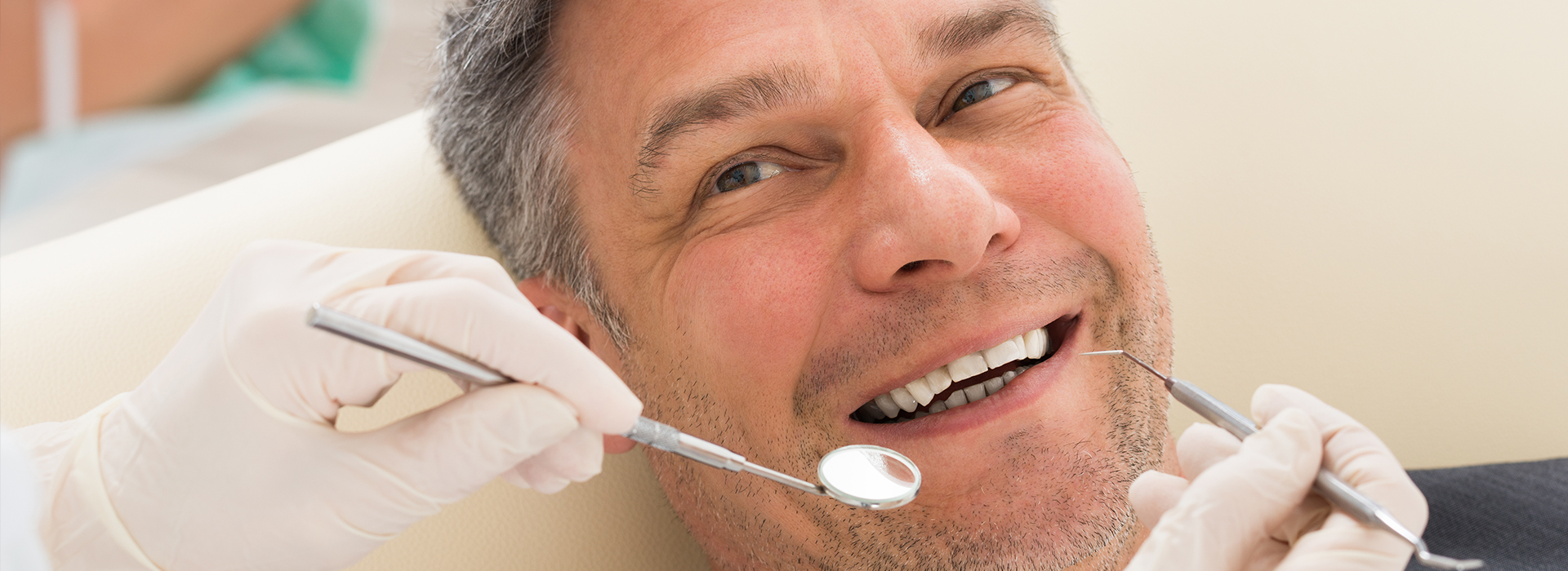 A man in a dental chair receiving dental treatment, surrounded by dental tools and equipment.